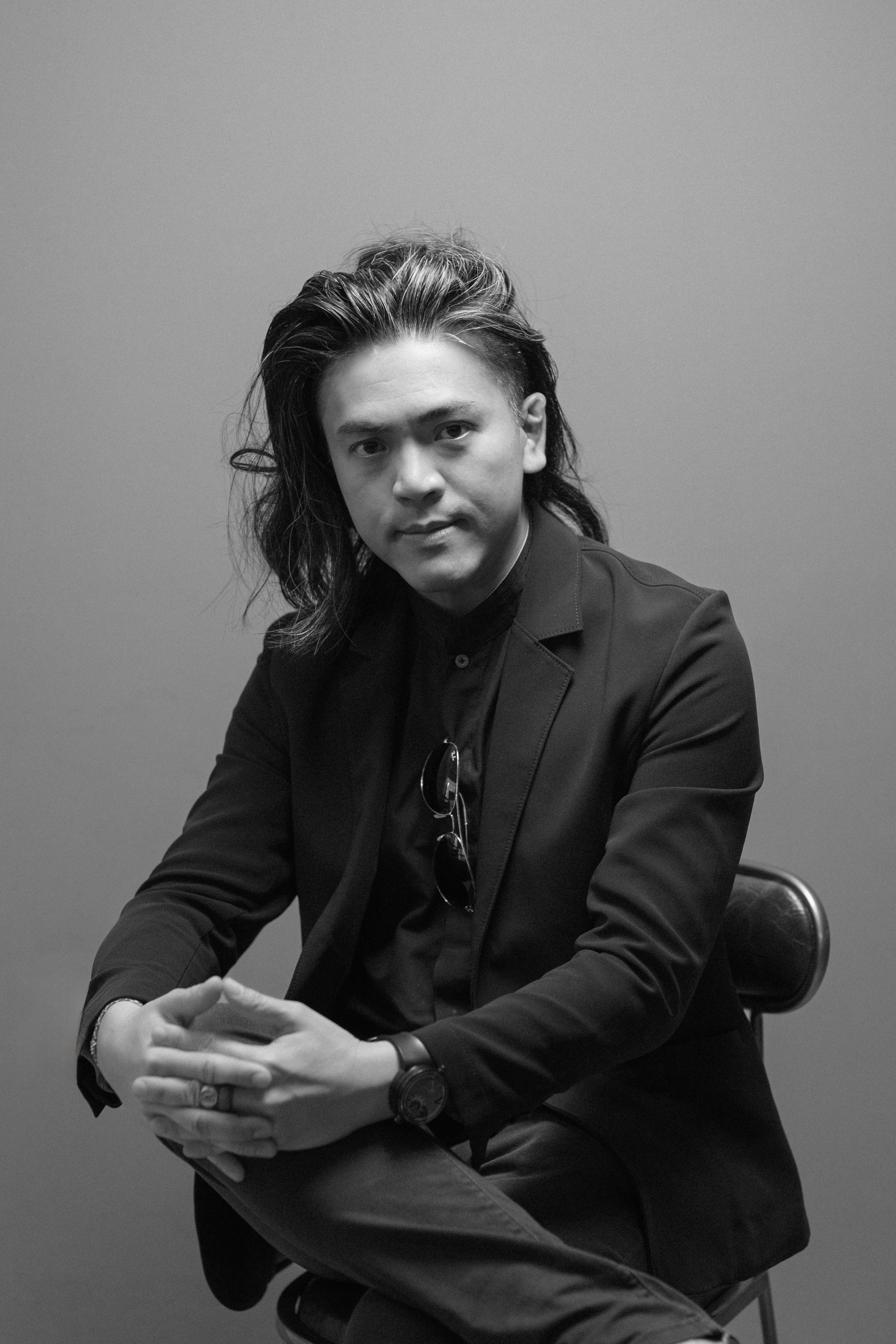 Black-and-white portrait of Dr Aaron Kwan seated in a studio