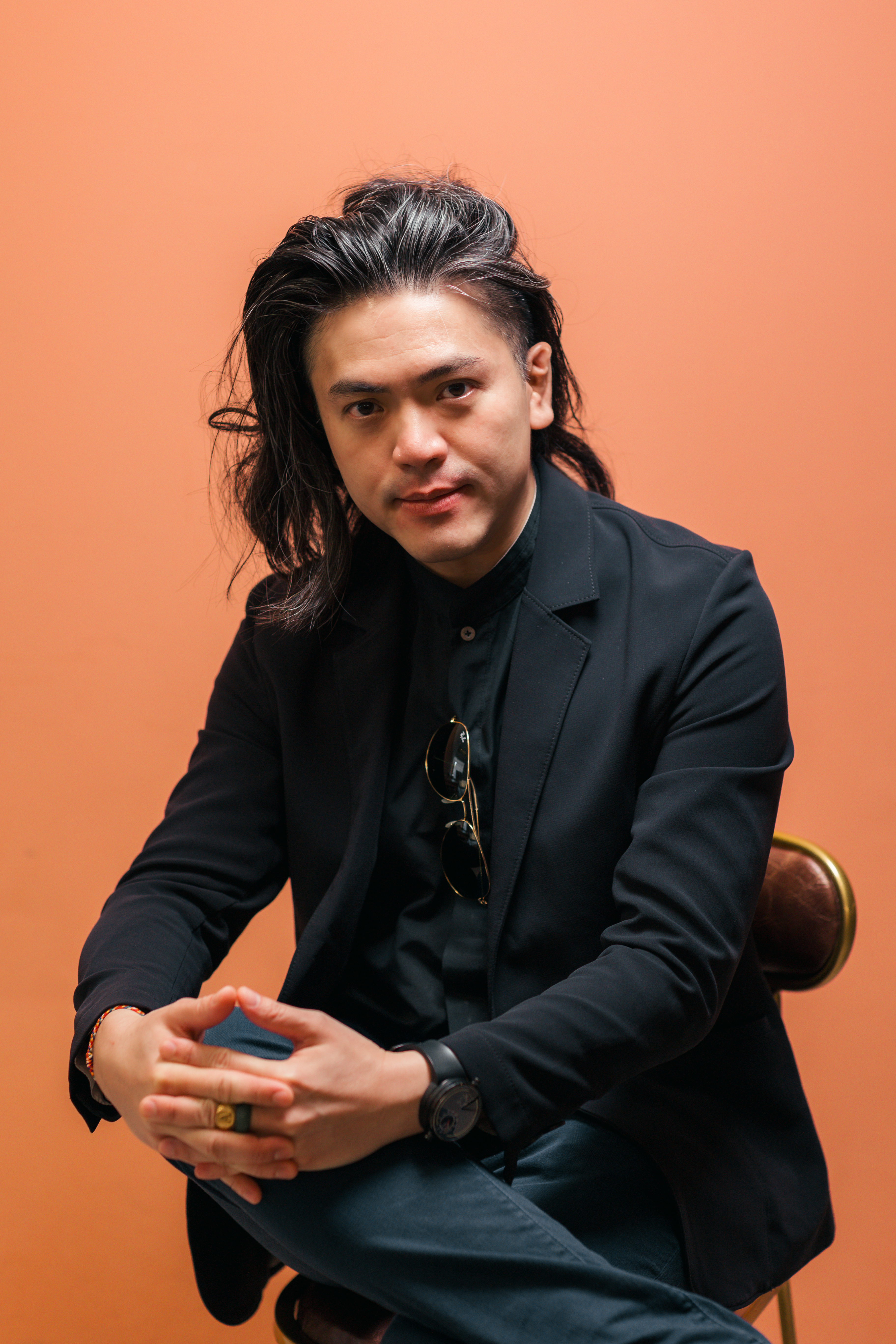 Dr. Aaron Kwan seated against an orange studio backdrop